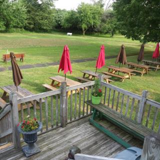 A view of an outdoor dining area featuring wooden tables and colorful umbrellas on a sunny day.