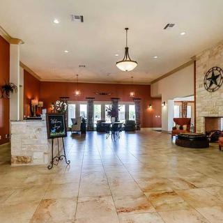 A spacious and elegant lobby with a chandelier and fireplace, featuring tile flooring.