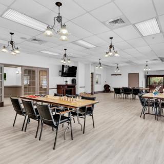 A modern dining area with tables and chairs arranged in an open space, featuring contemporary lighting fixtures.