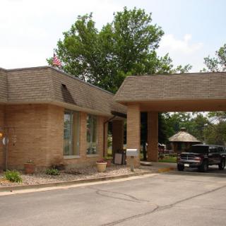 A drive-thru entrance to a building, surrounded by trees.
