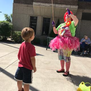 A cheerful clown performs for a young child, bringing joy to an outdoor event.