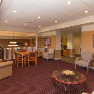 A comfortable seating area in a lobby featuring various chairs and tables under ceiling lights.