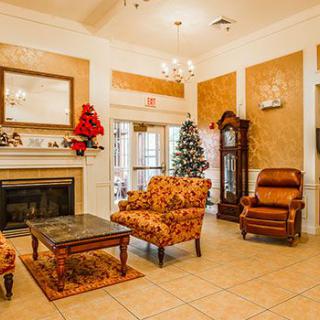 A cozy living room with elegant decor, featuring a fireplace, armchairs, and a Christmas tree.