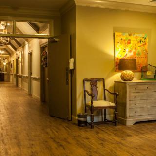 A warm and inviting hallway with wooden floors, elegant furniture, and vibrant artwork on the wall.
