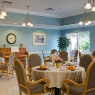 A cozy dining area in a senior living facility, featuring elegantly set tables and a piano for ambiance.