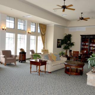 A spacious and elegantly furnished living room with large windows, multiple seating areas, and tasteful decor.