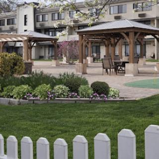 A serene outdoor space featuring wooden gazebos, manicured gardens, and a lush green lawn.