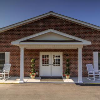 A welcoming entrance to a brick building with rocking chairs on the porch.