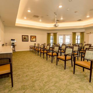 An empty meeting room with rows of chairs arranged for a presentation or conference.
