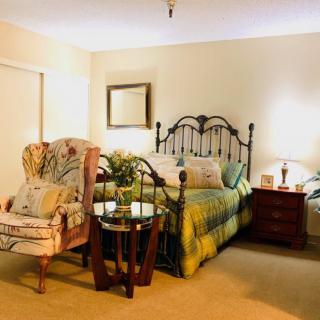 A cozy bedroom with a metal bed frame, an armchair, and ambient lighting.