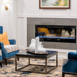 A modern living room with blue chairs and a fireplace, featuring stylish decor.