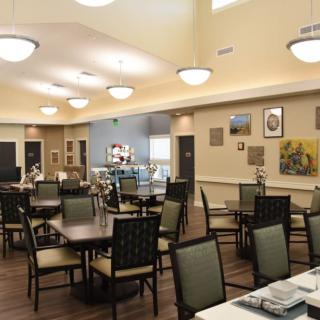 A well-lit dining area with neatly arranged tables and chairs, adorned with wall decorations.