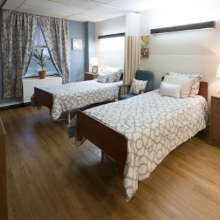 A well-lit hospital room featuring two neatly arranged beds with patterned bedding.