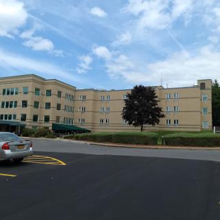 A view of a large institutional building with a landscaped area and clear blue sky.