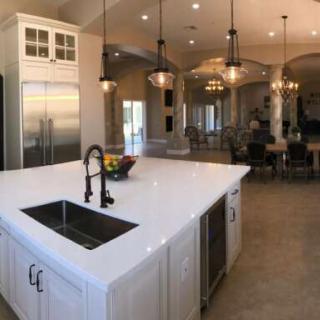 A modern kitchen with a large island and stainless steel appliances, featuring elegant lighting in an open space.