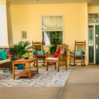 A cozy porch with wooden rocking chairs, a coffee table, decorative pillows, and potted plants.