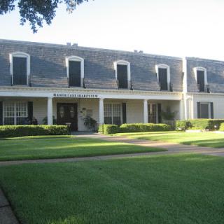 A charming two-story house featuring classic architectural elements and a well-maintained front lawn.