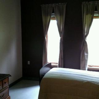 A cozy bedroom with two windows, curtains, and a bed.