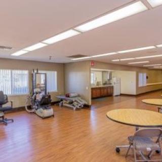 A spacious rehabilitation facility featuring exercise equipment and seating areas with bright lighting.