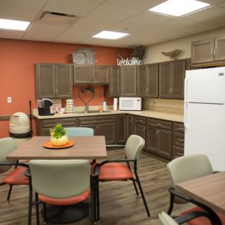 A modern kitchen and dining area with tables, chairs, and appliances.