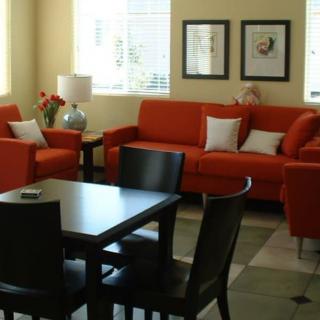 A modern living room with orange sofas and a dining table.