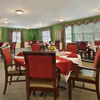 A cozy dining room with elegantly set tables adorned in red and green decor.