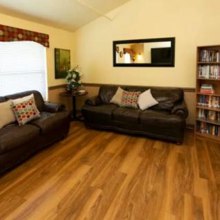 A cozy living room featuring two sofas, decorative cushions, a mirror on the wall, and a wooden floor.