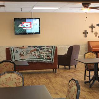 A cozy lounge area with a television, seating arrangements, and decorative crosses on the wall.