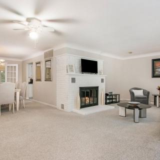 A modern living room with a fireplace and an adjacent dining area, featuring a carpeted floor and contemporary furnishings.