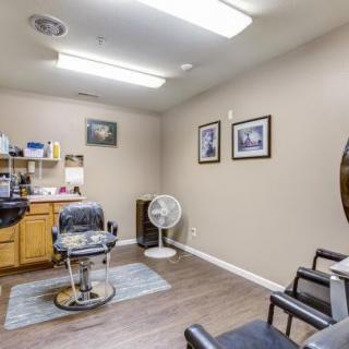 An interior view of a barber shop with chairs, mirrors, and framed pictures on the wall.