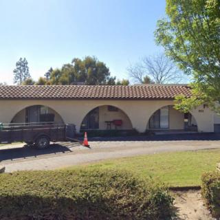 A building with arches under a clear, sunny sky surrounded by trees.