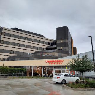 A modern hospital building under a cloudy sky, featuring a clearly marked entrance.