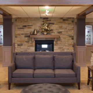 A cozy living room with a dark sofa and a stone fireplace.