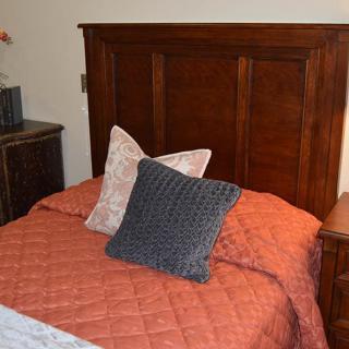 A cozy bedroom setting featuring a wooden headboard and neatly arranged pillows on the bed.
