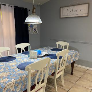 A cozy dining room setup featuring a floral tablecloth, elegant chairs, and stylish lighting.