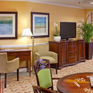 A cozy living room featuring a TV, elegant wooden furniture, and decorative paintings on the wall.