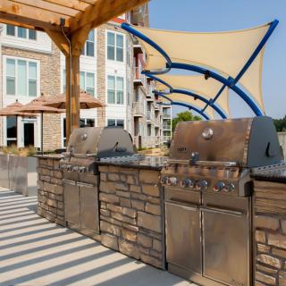 Outdoor kitchen area with grills and shade structures on a sunny day.