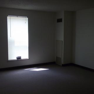 An empty room with a single window allowing natural light to enter.