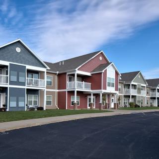 A row of modern suburban apartment buildings with colorful facades under a clear blue sky.