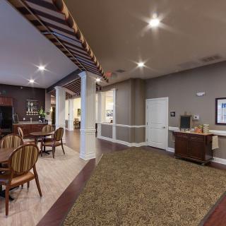 A cozy lounge area featuring wooden chairs and tables, with soft lighting and elegant decor.