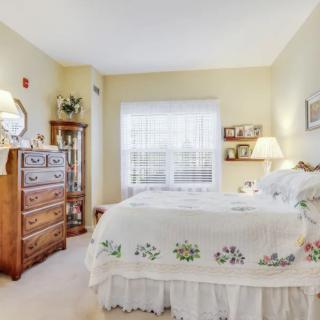 A cozy vintage-style bedroom with a neatly made bed, wooden dresser, and soft lighting from a lamp.
