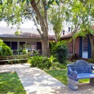 A tranquil garden setting with a house, trees, and a blue bench alongside a pathway.