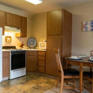 A cozy kitchen with wooden cabinets, a small dining table, and essential appliances.