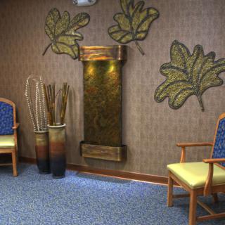 A cozy waiting room with decorative plants, a water feature, and comfortable chairs.