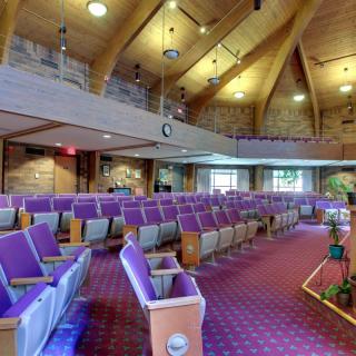 Interior view of a church featuring wooden ceilings and purple seating.