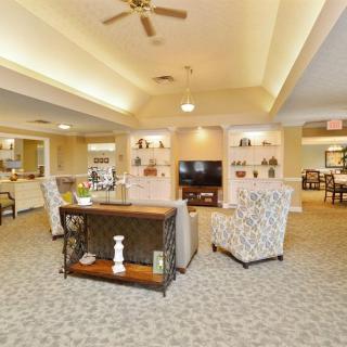 A spacious and elegantly decorated living room with comfortable seating, a television, and built-in shelving.