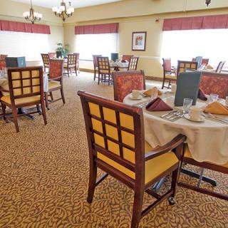 A well-lit dining room with neatly arranged tables and chairs, featuring elegant table settings.