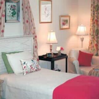 A cozy bedroom with a neatly made bed, decorative pillows, and warm lighting.