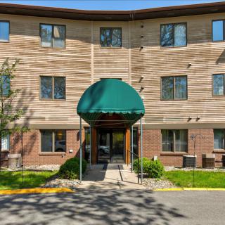 An exterior view of a residential apartment building with a green awning over the entrance.