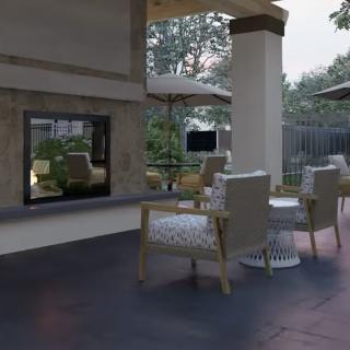 A cozy outdoor patio area featuring comfortable seating, a fireplace, and garden views.
